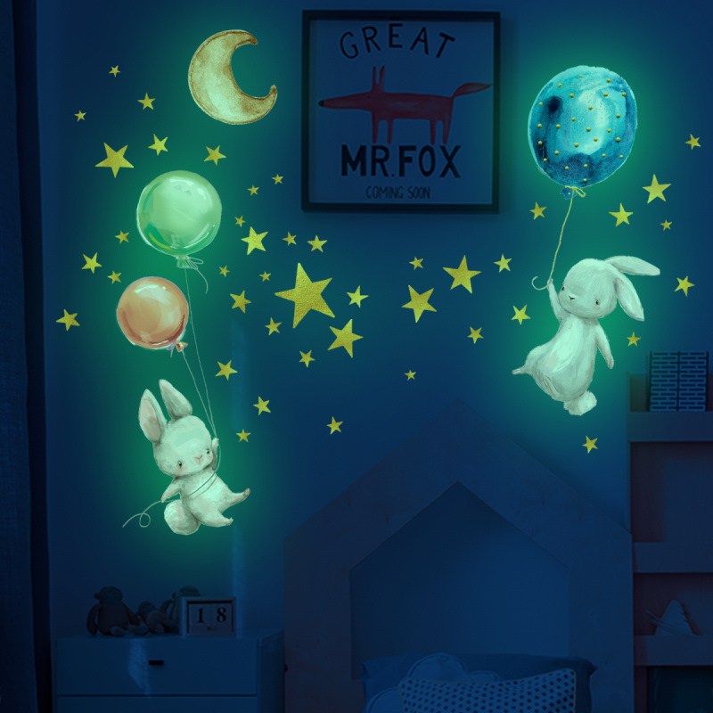 Billede af Sød selvlysende wallsticker med to små kaniner der svæver med balloner, omgivet af masser af stjerner.